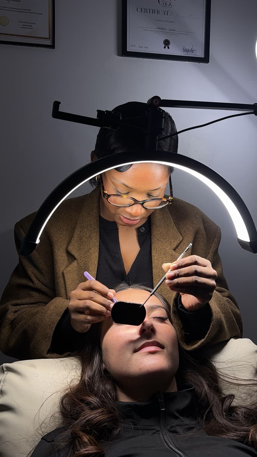 Technicienne de cils qui vérifie sa pose au miroir